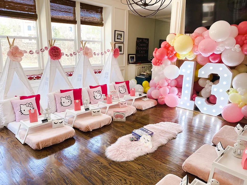 Coral, pink and white balloon garland beside light up numbers at a teepee sleepover