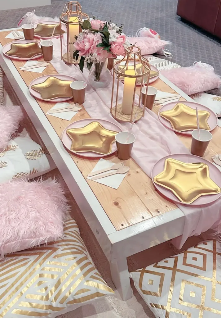 Luxe picnic table styled in pink and gold with florals and place settings