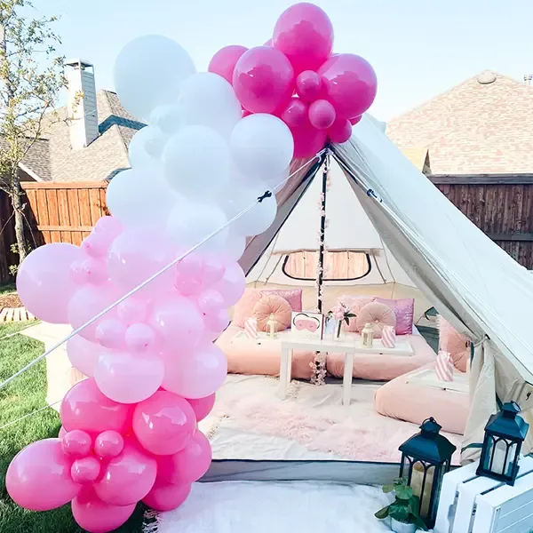 Hot pink, pink and white balloon garland over an outdoor bell tent