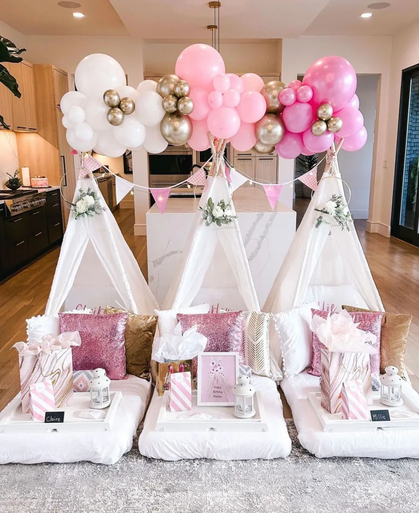 Pink, gold and white balloon clouds above three styled teepees