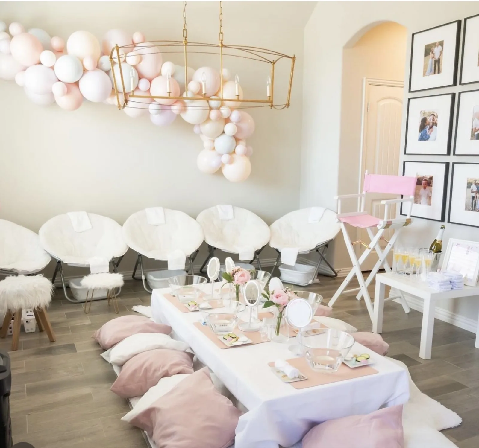 Spa party set-up with pastel balloon garland, spa table and pedicure chairs