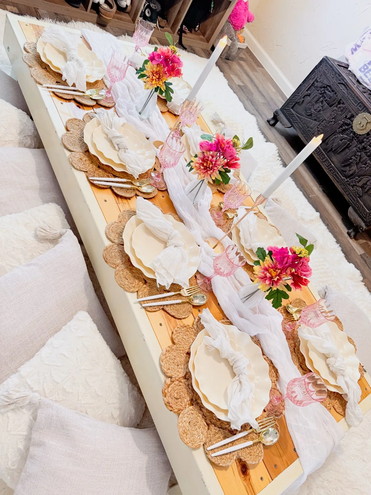 Luxe picnic table with jute placemats, gold cutlery, candles and florals