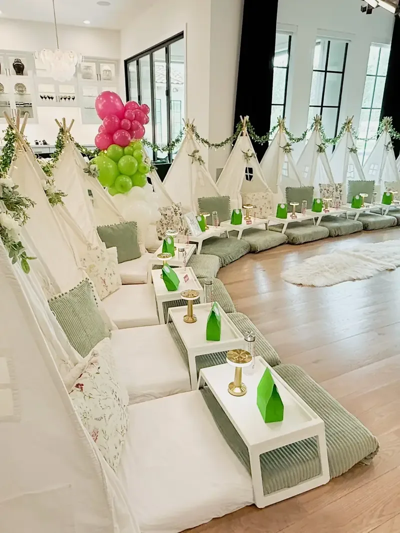 Row of styled teepees with breakfast trays and floral cushions
